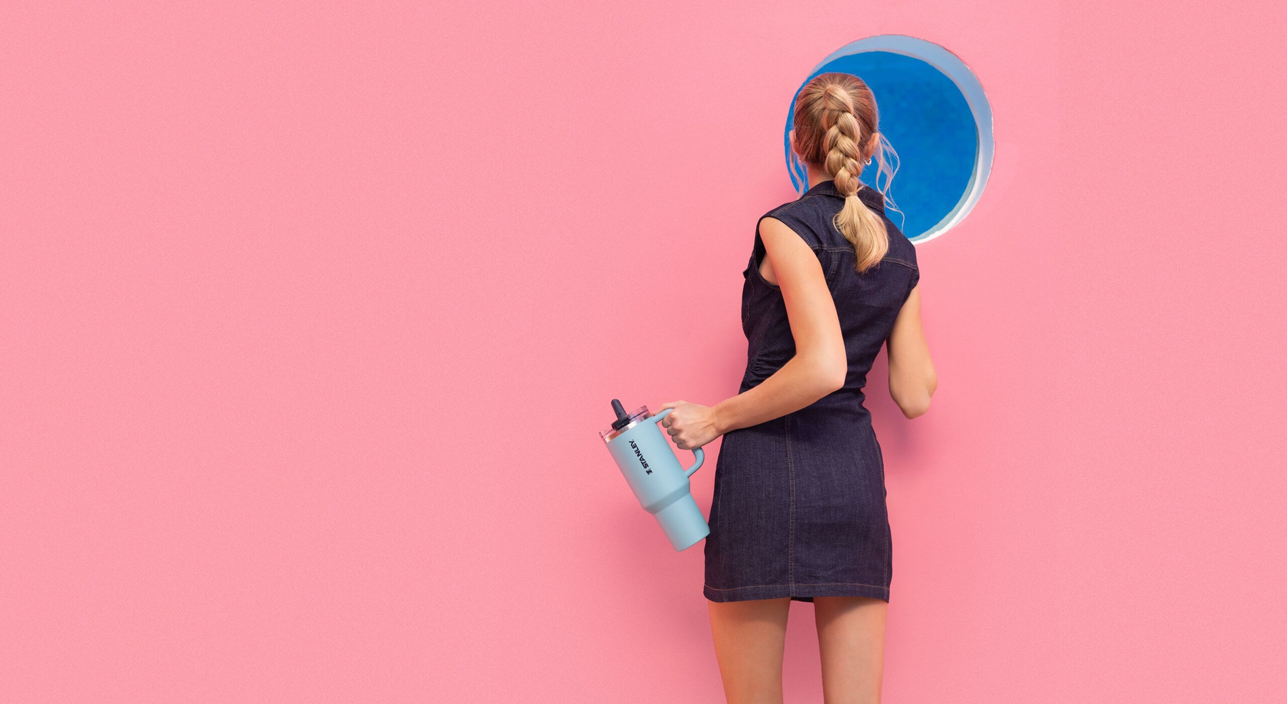 Woman holding a blue Quencher against a pink background